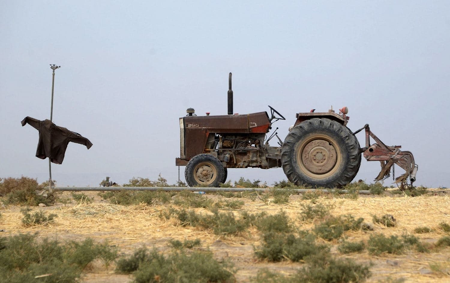 A tractor is parked near a scarecrow on agricultural land on the outskirts of the the town of Tel Kaif, north of Mosul on October 26, 2021. Photo: Zaid al-Obeidi/AFP