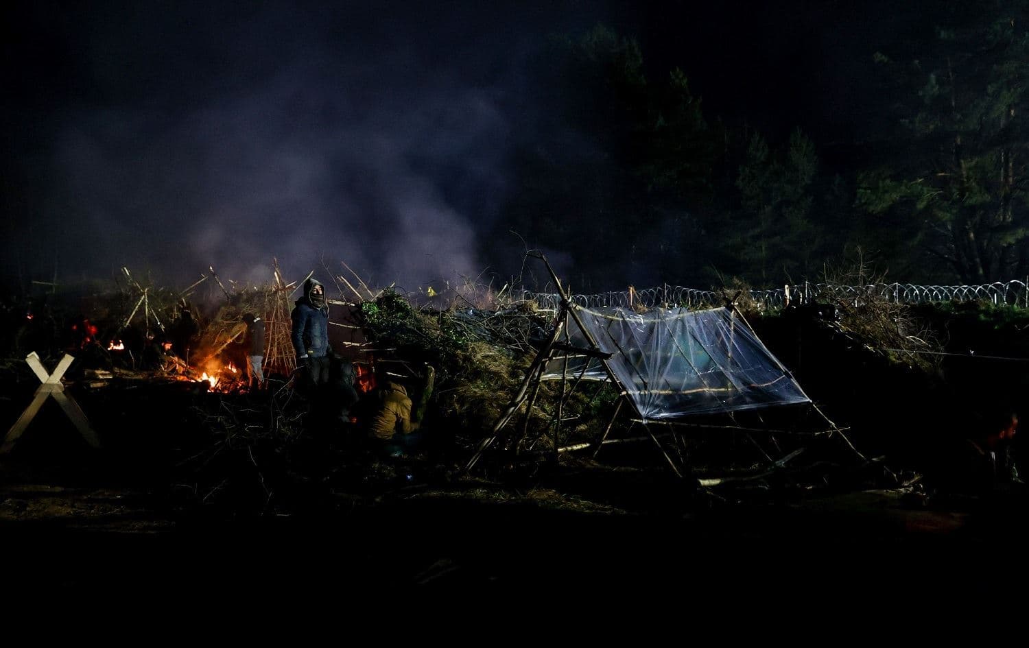 Migrants warm themselves by fires in a camp on the Belarusian-Polish border in the Grodno region on November 14, 2021. Photo: Oksana Manchuk/BELTA/AFP