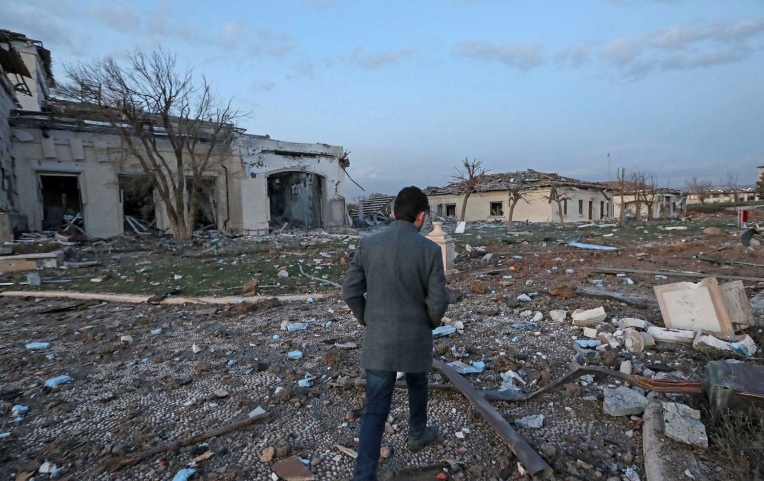 A man walks past damaged civilian properties following the missile strike on Erbil on March 13, 2022. Photo: Safin Hamed/AFP