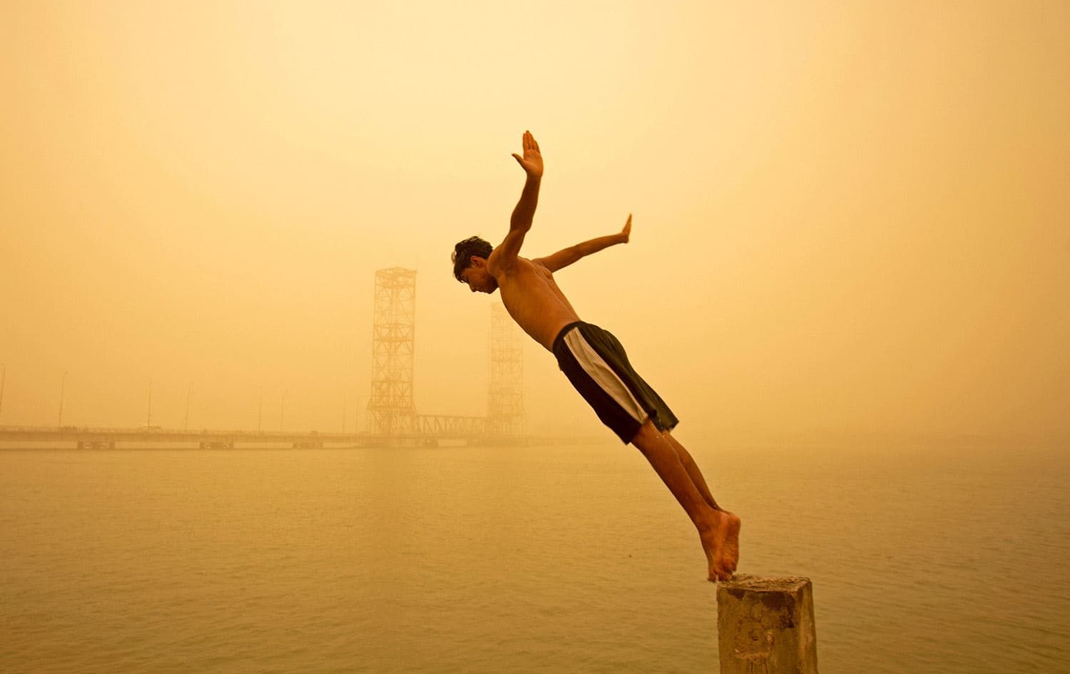 A youth dives in the Shatt al-Arab river during a sandstorm in Iraq's southern city of Basra on May 16, 2022. Photo: Hussein Faleh/AFP