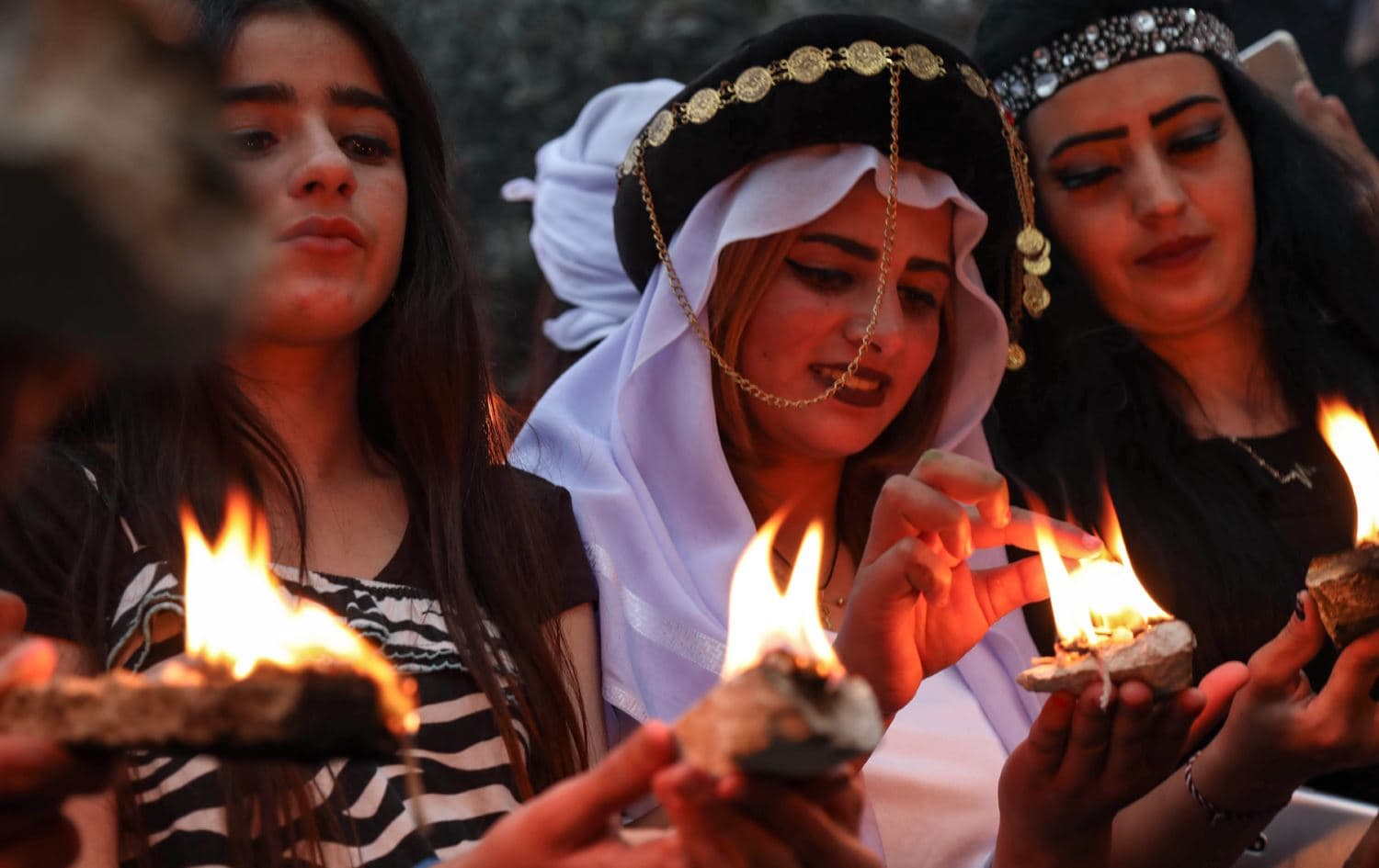 Yazidi women hold candles outside of Lalish Temple in Duhok. Photo: Safin Hamed/AFP