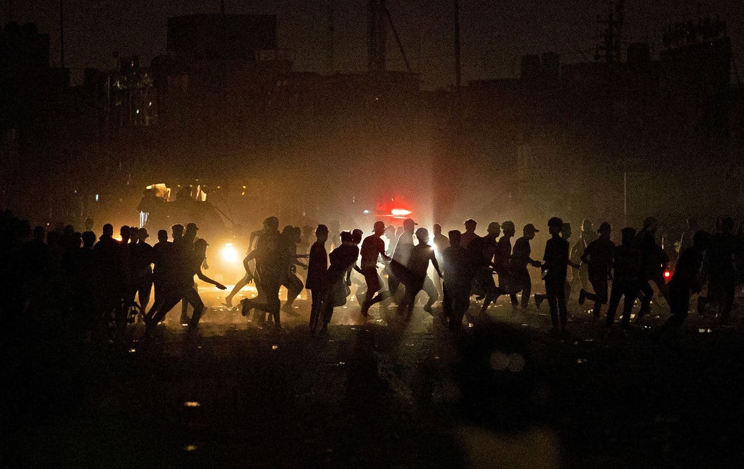 Iraqi protesters sprint away as security forces deploy during a rally to mark three years since nationwide demonstrations erupted against endemic corruption, in the southern city of Basra, on October 1, 2022. Photo: Hussein Faleh/AFP