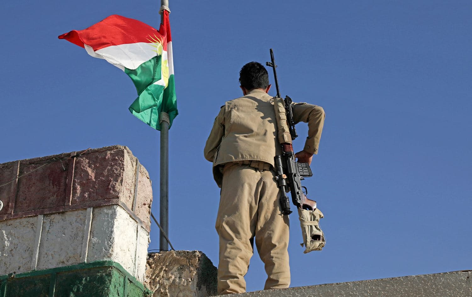 A Kurdish Peshmerga fighter affiliated with the Kurdistan Democratic Party of Iran (KDPI) stands guard on a building following an Iranian cross-border attack in the town of Koya on October 1, 2022. Photo: Safin Hamed/AFP