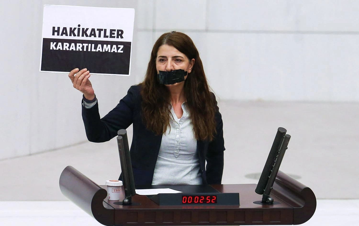 Peoples' Democratic Party's Zuleyha Gulum holds a banner "Truths cannot be obscured" as she stands with a covered mouth at the Turkish Grand National Assembly in Ankara on October 13, 2022, Photo: Adem Altan/AFP