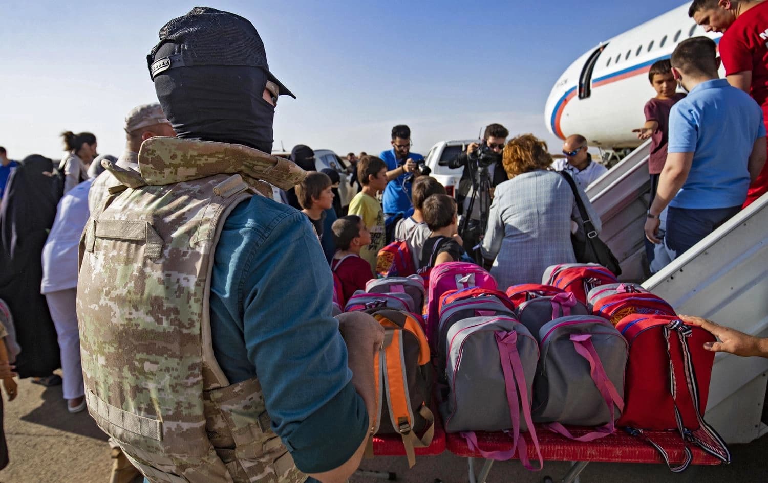 A group of children, among 38 from families of suspected Islamic State (IS) group, are protected by Russian soldiers, as they board a plane before being repatriated to Russia, at the airport of the city of Qamishli in Syria's northeastern Hasaka province, on October 20, 2022. Photo: Delil Souleiman/AFP