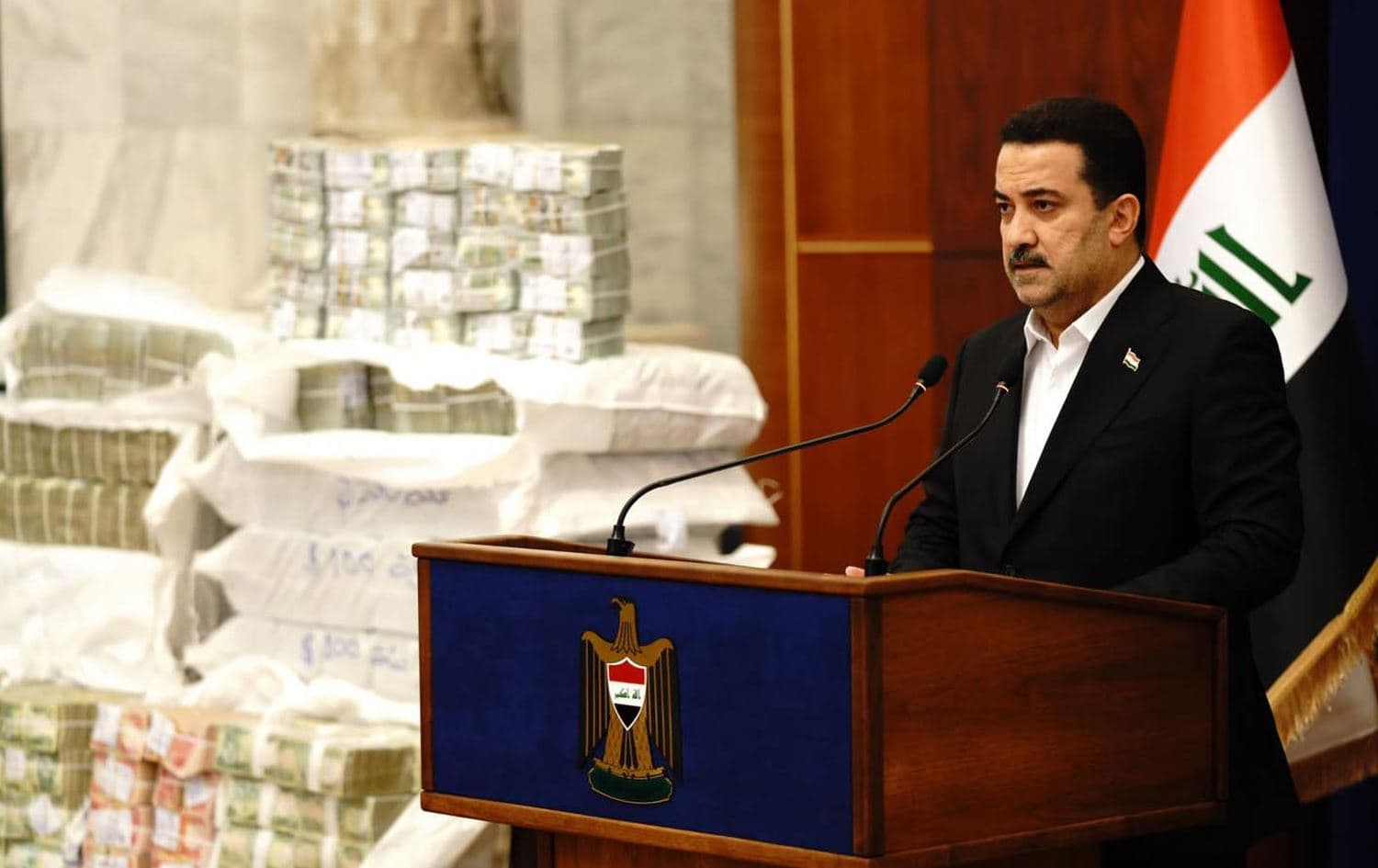 Iraqi Prime Minister Mohammed Shia’ al-Sudani standing before piles of cash retrieved from the $2.5 billion stolen in tax funds on November 27, 2022. Photo: PM Sudani’s office