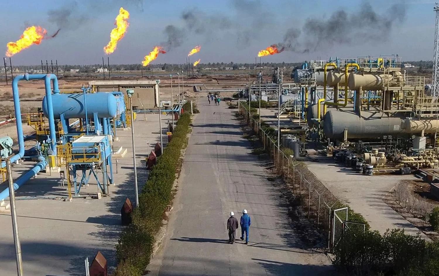 Workers walk down a path in the Nihran Bin Omar oil field north of southern Iraq’s oil-rich city of Basra. Photo: Nabil al-Jurani/AFP