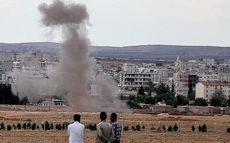 Refugees look on as smoke rises near the Kurdish border town of Kobane during an attack from Islamic State fighters, in this AFP file photo. 
