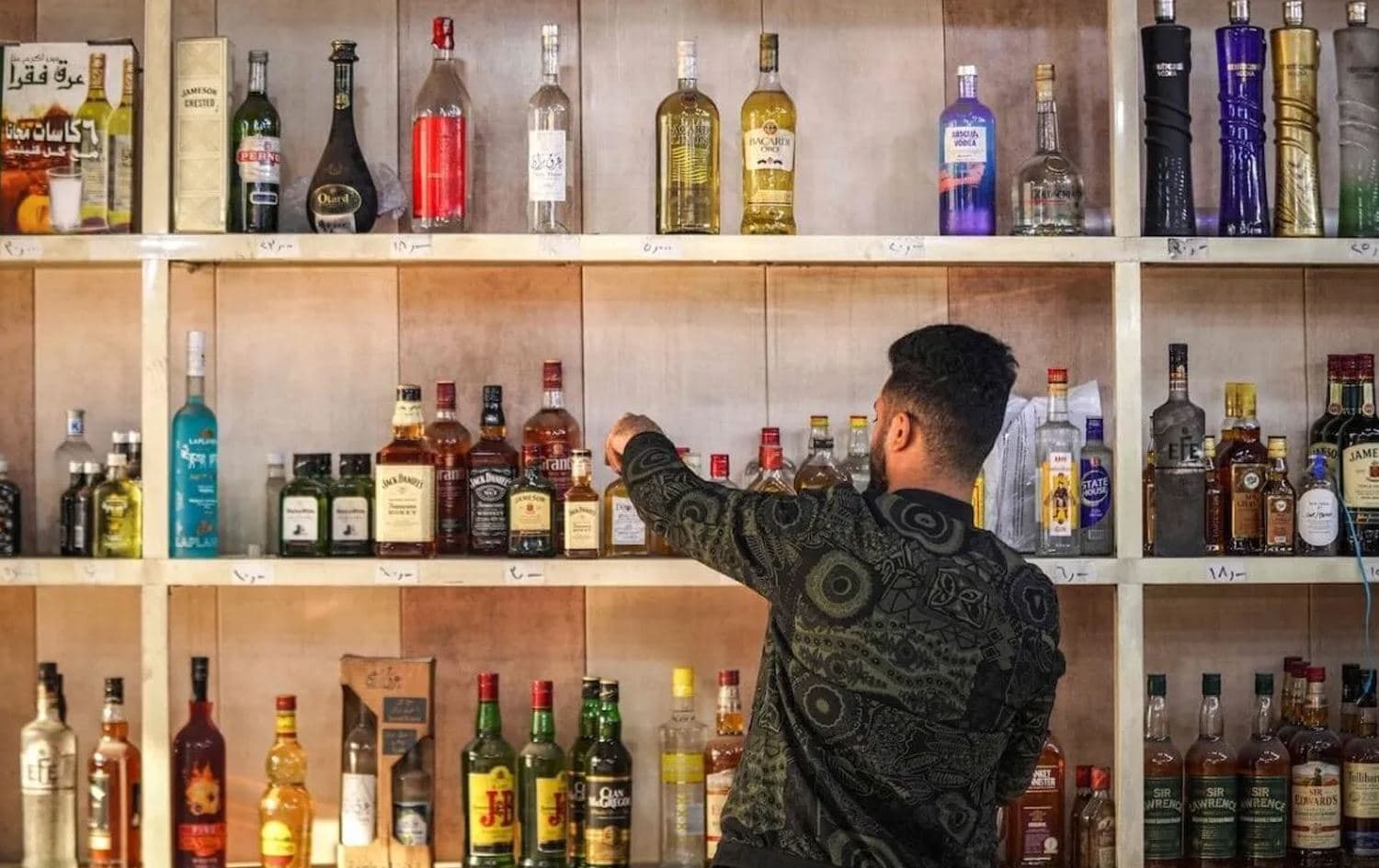 A shopworker arranges whisky bottles on a shelf at a liquor shop in the Bataween district in the center of Iraq's capital Baghdad on December 5, 2020. Photo: Ayman Henna/AFP