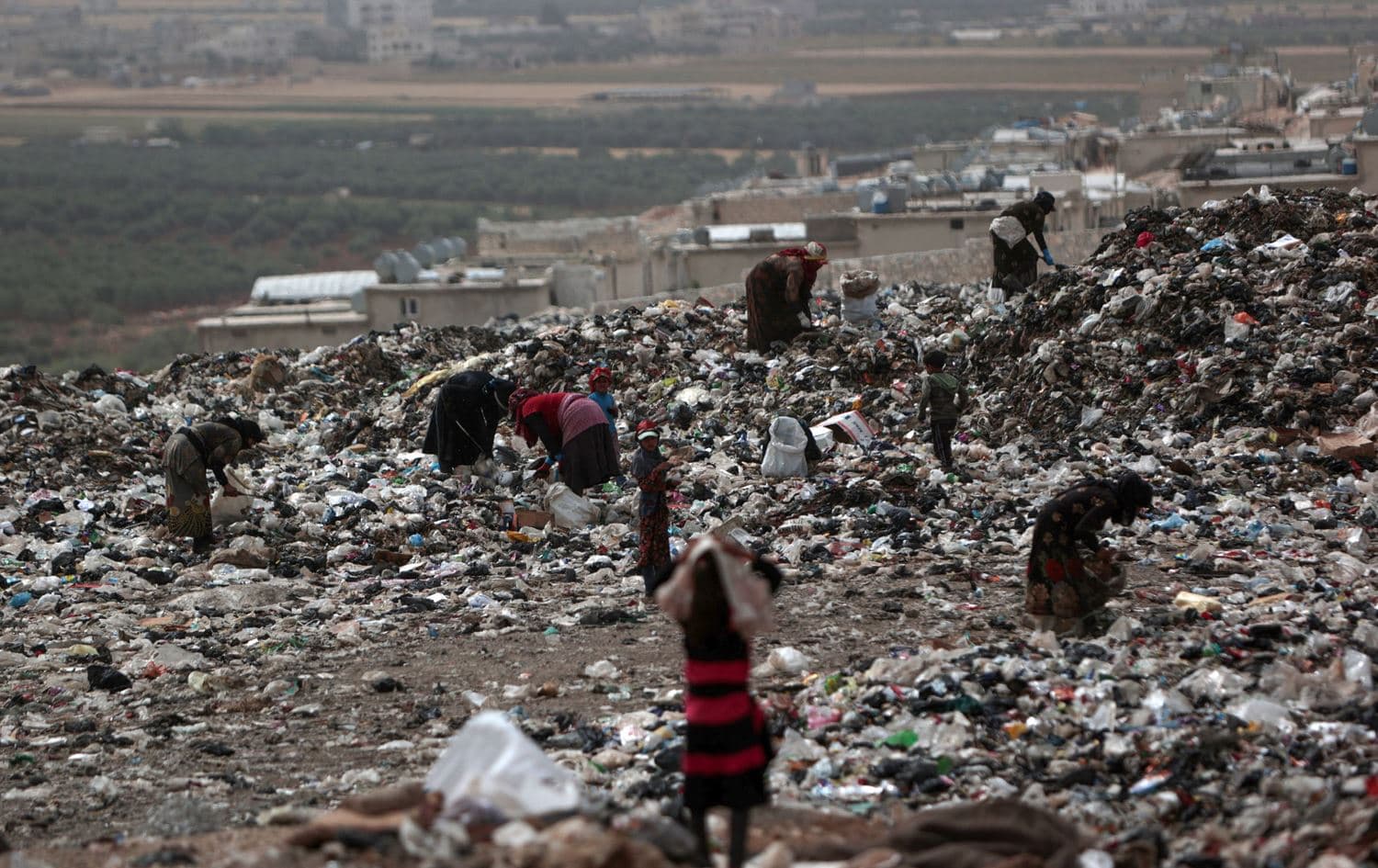 In this picture taken on June 3, 2023, women and children sift through rubbish, as they look for plastic items to sell for recycling, at a dump site near the village of Hazreh in Syria's northwestern Idlib province. Photo: Aaref Watad/AFP
