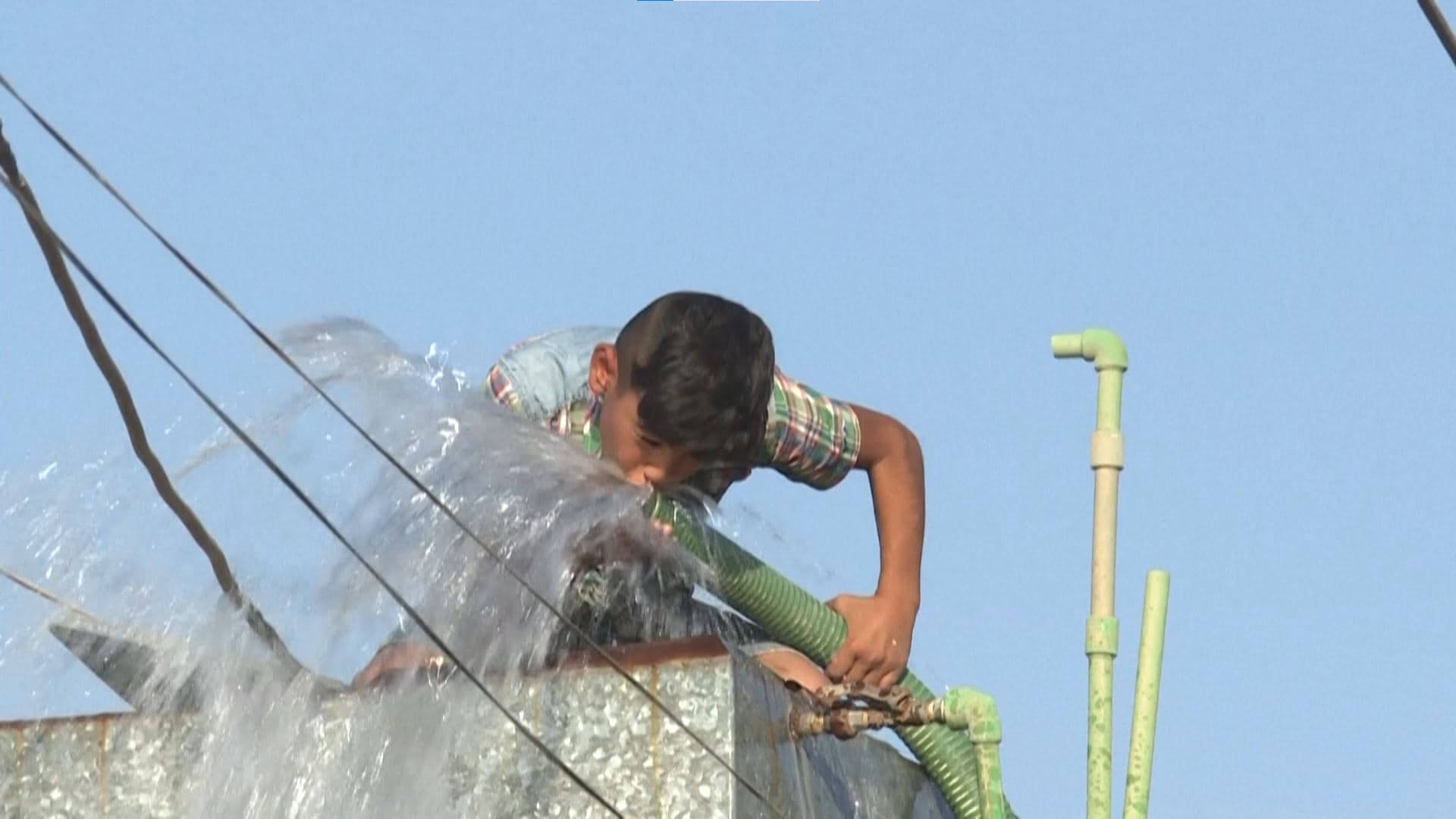 A child drinks water from a hose in Hasaka in August 2020. Photo: AFP 