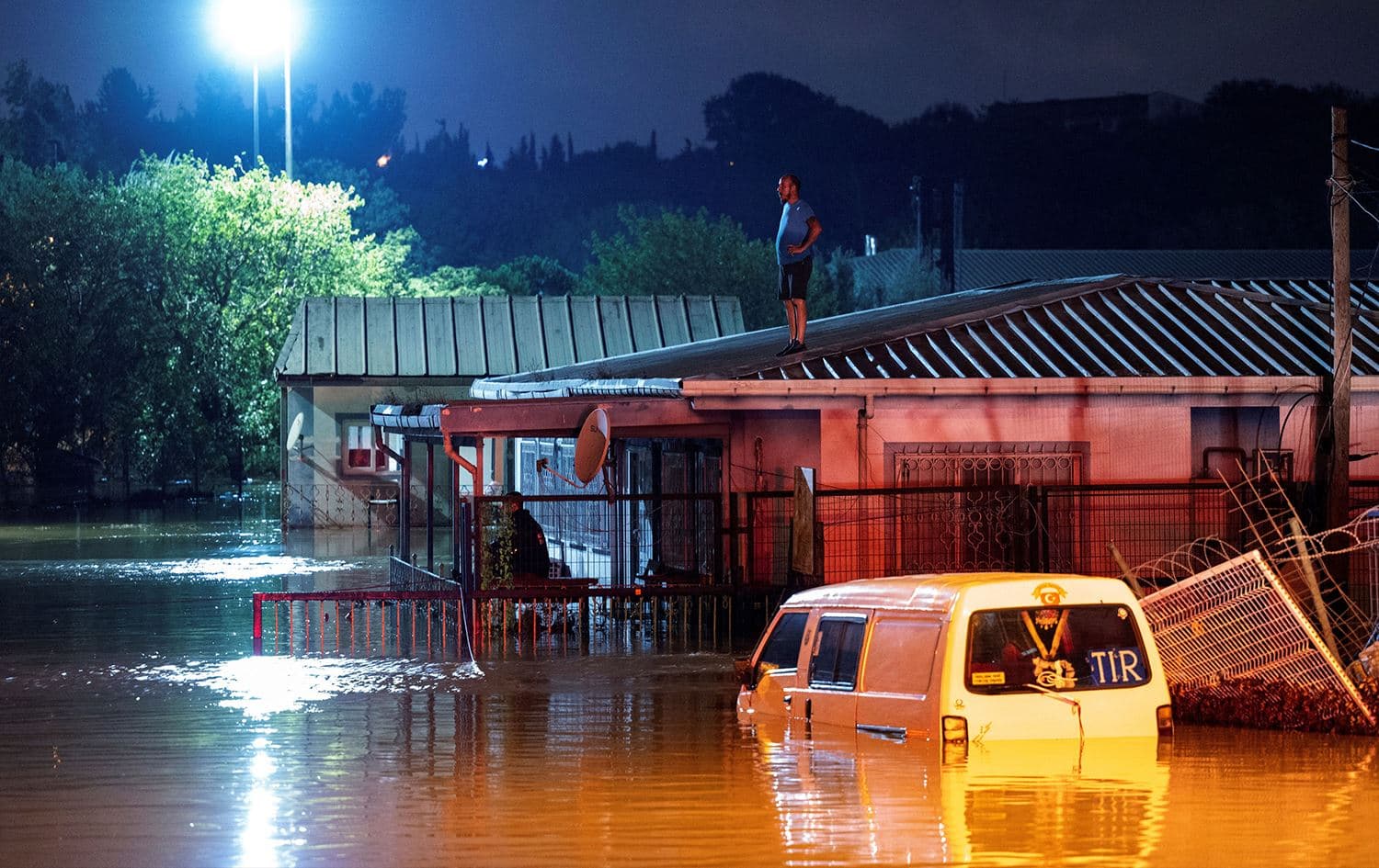 A man stands on a roof waiting to be rescued by boat during flooding in Kucukcekmece district in Istanbul on September 5, 2023. Two people died on Tuesday in flash floods from torrential rains that turned the streets of Istanbul into rushing rivers, officials said. Photo: Yasin Akgul/AFP