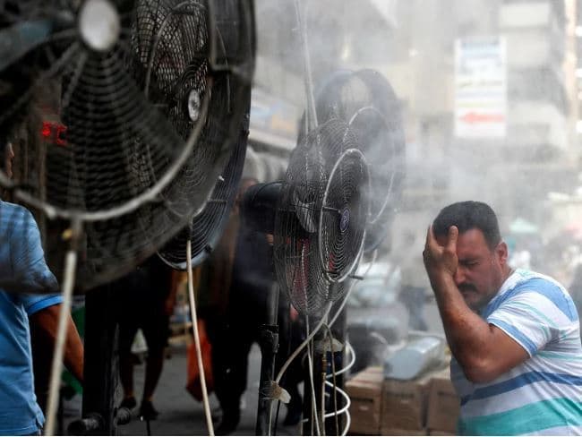 Fans spray air mixed with water vapor to cool down pedestrians on a Baghdad street on June 30, 2021, during a heat wave. Photo: Ahmad al-Rubaye/AFP