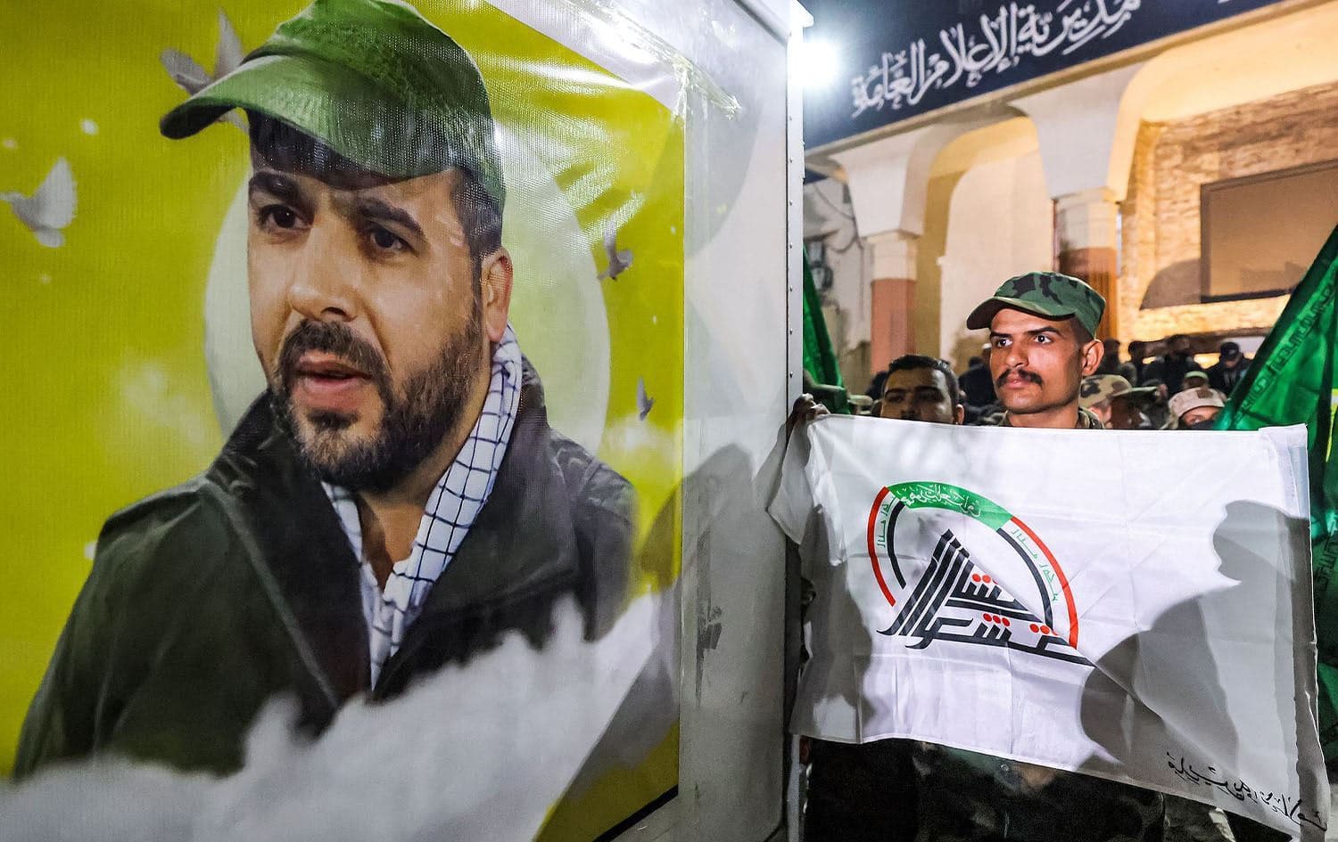 A member of the PMF holds the group’s flag while standing before the vehicle carrying the body of a slain commander of Harakat al-Nujaba, Mushtaq Talib al-Saeedi, in Baghdad on January 4, 2024. Photo: AFP