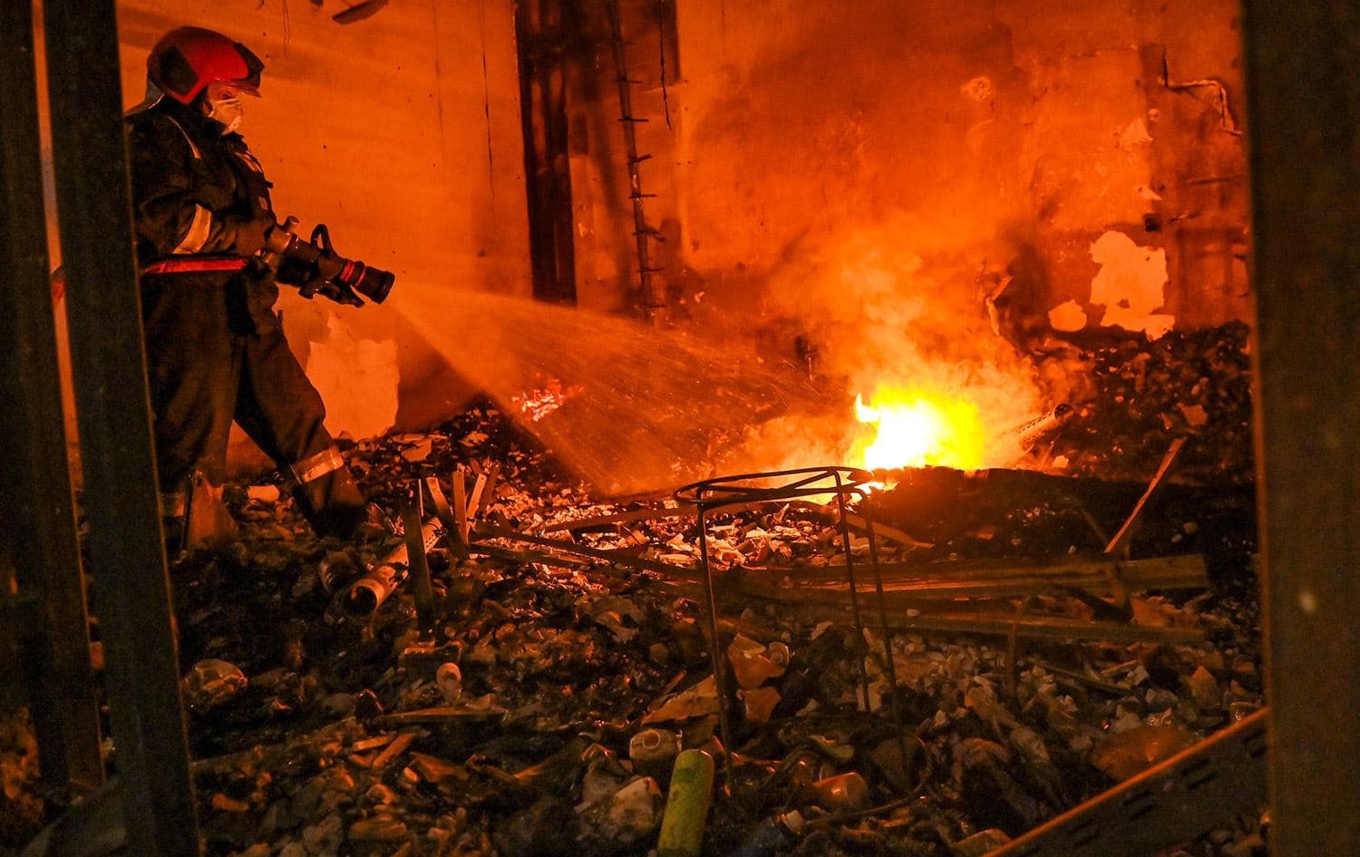 کارمەندێکی بەرگریی شارستانیی هەولێر ئاگری نێو دووکانێکی بازاڕی لەنگە دەکوژێنێتەوە. وێنە: بڵند تاهیر - رووداو