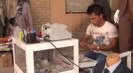 Exchange worker puts his Iraqi dinar in order at the Market near Kurdistan's citadel.