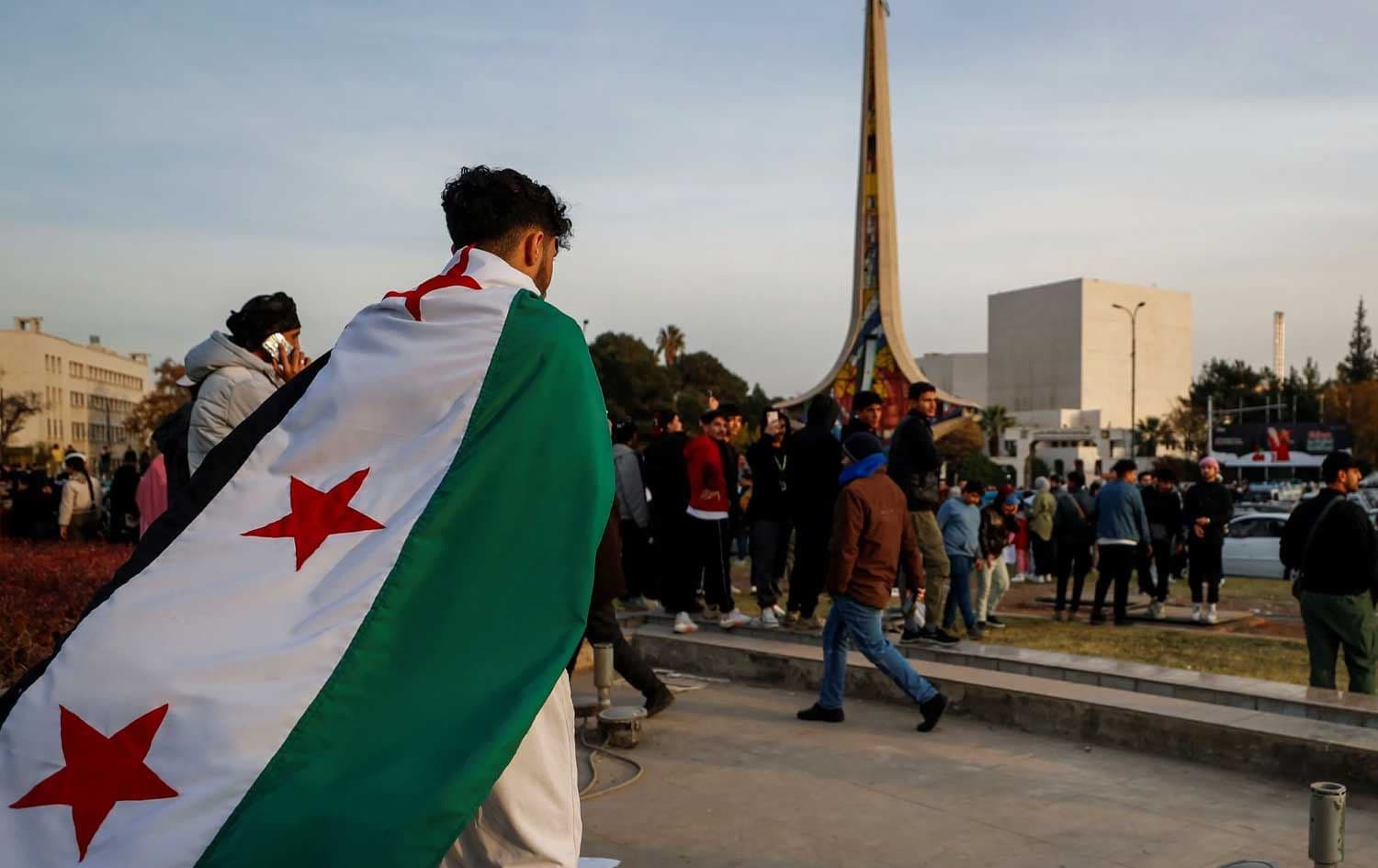 گەنجێکی سووریایی کە ئاڵای پەسندکراو لەلایەن ئۆپۆزیسیۆنی سووریای لەسەر شانە؛ وێنە: AP