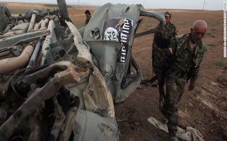 Kurdish Peshmerga forces inspect an ISIS vehicle destroyed by an American airstrike. Photo: AFP