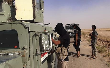 ISIS fighters inspect abandoned Iraqi Army vehicles. AFP photo.