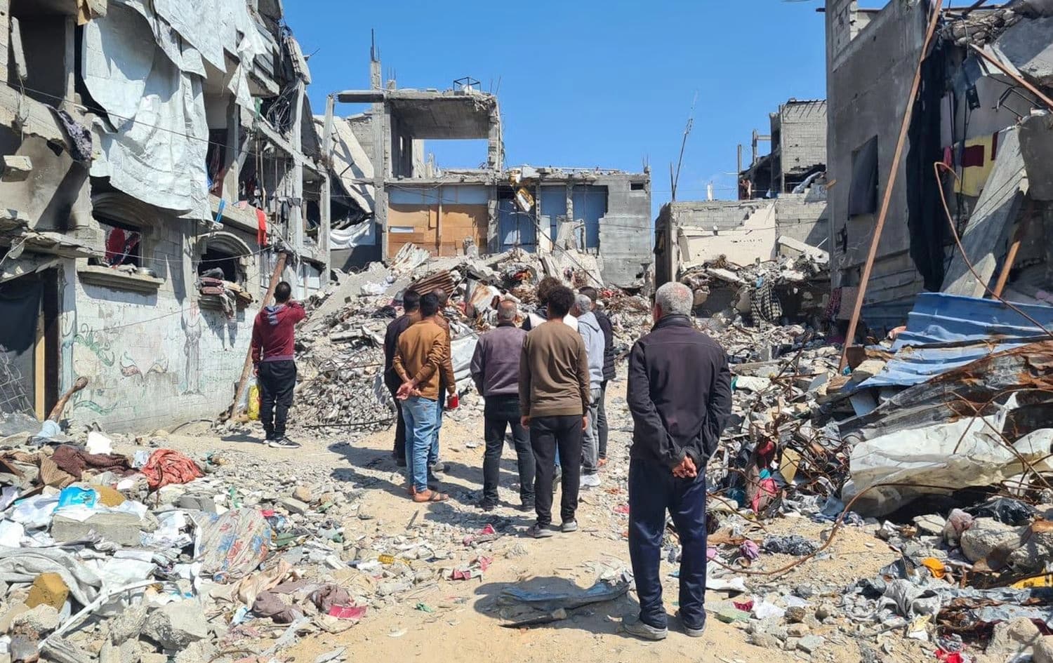 چەند کەسێک لە غەززە سەیری خانووە رووخاوەکانیان دەکەن