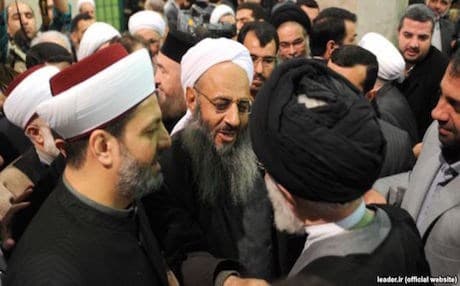 Abdulhamid (center) shaking hands with Khamenei during the conference. 