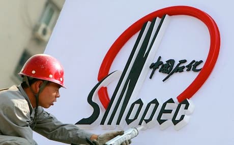 A Chinese worker installs a Sinopec logo at a new station in Beijing. Photo: AFP