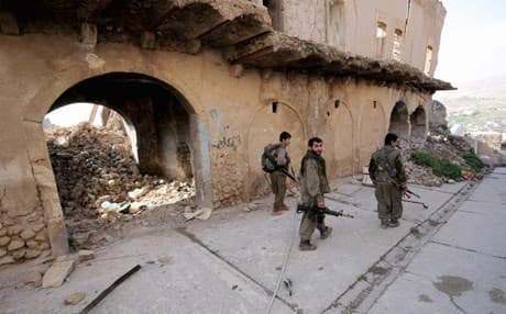 PKK fighters walk through the damaged town of Shingal. AP file photo