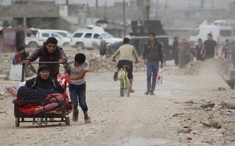 Locals walk in a liberated eastern-Mosul neighborhood with an Iraqi army vehicle in the background. Photo: Rudaw