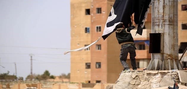 A member of the US-backed Syrian Democratic Forces (SDF) removes an ISIS group flag in the town of Tabqa, about 55 kilometres west of the ISIS-held of Raqa city. Photo: AFP/Delil Souleiman