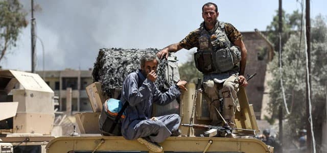 A displaced Iraqi man is escorted by Iraqi forces after fleeing his home in Mosul's western Al-Shifa district on June 15, 2017. More than half a million people have fled their homes since the operation to retake western Mosul began in February this year. Photo: AFP/Mohamed El-Shahed