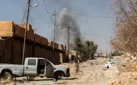 Smoke billows in the background past damaged vehicles as Iraqi forces, backed by the Hashd al-Shaabi units, advance inside the town of Tal Afar, west of Mosul. Photo: Ahmed Al-Rubaye/AFP