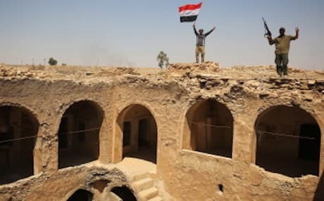 Fighters from the Hashd al-Shaabi, backing the Iraqi forces, pose with the Iraqi flag on Tal Afar's Ottoman-era historic citadel after troops took control of the area during an operation to retake the city from ISIS on August 27, 2017. Photo: AFP/Ahmad al-Rubaye