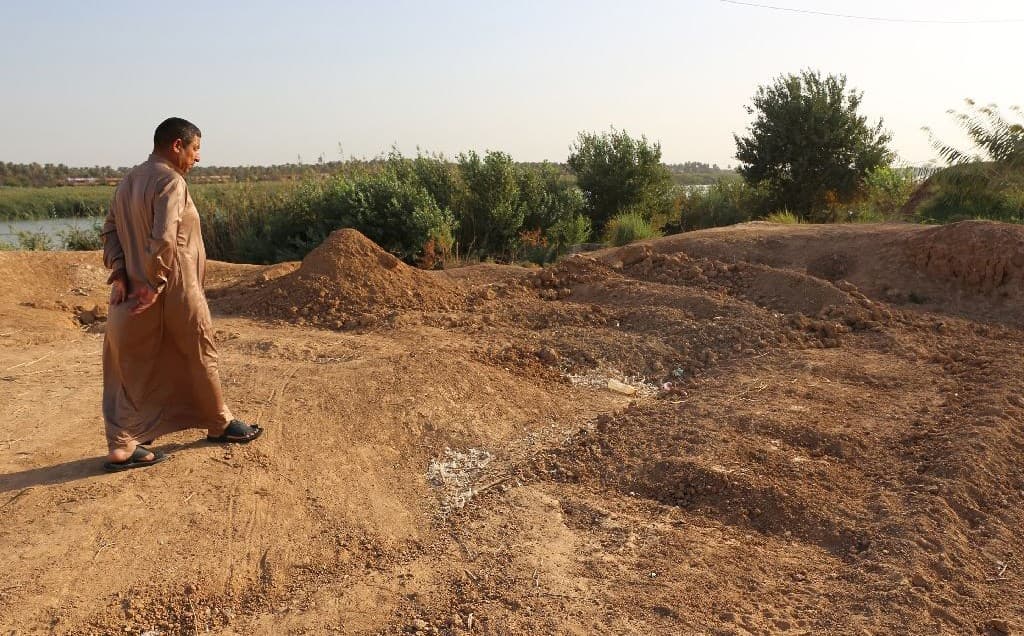 An Iraqi man walks by the site of a mass grave of ISIS fighters in Dhuluiyah, north of Baghdad. Photo: Sabah Arar/AFP