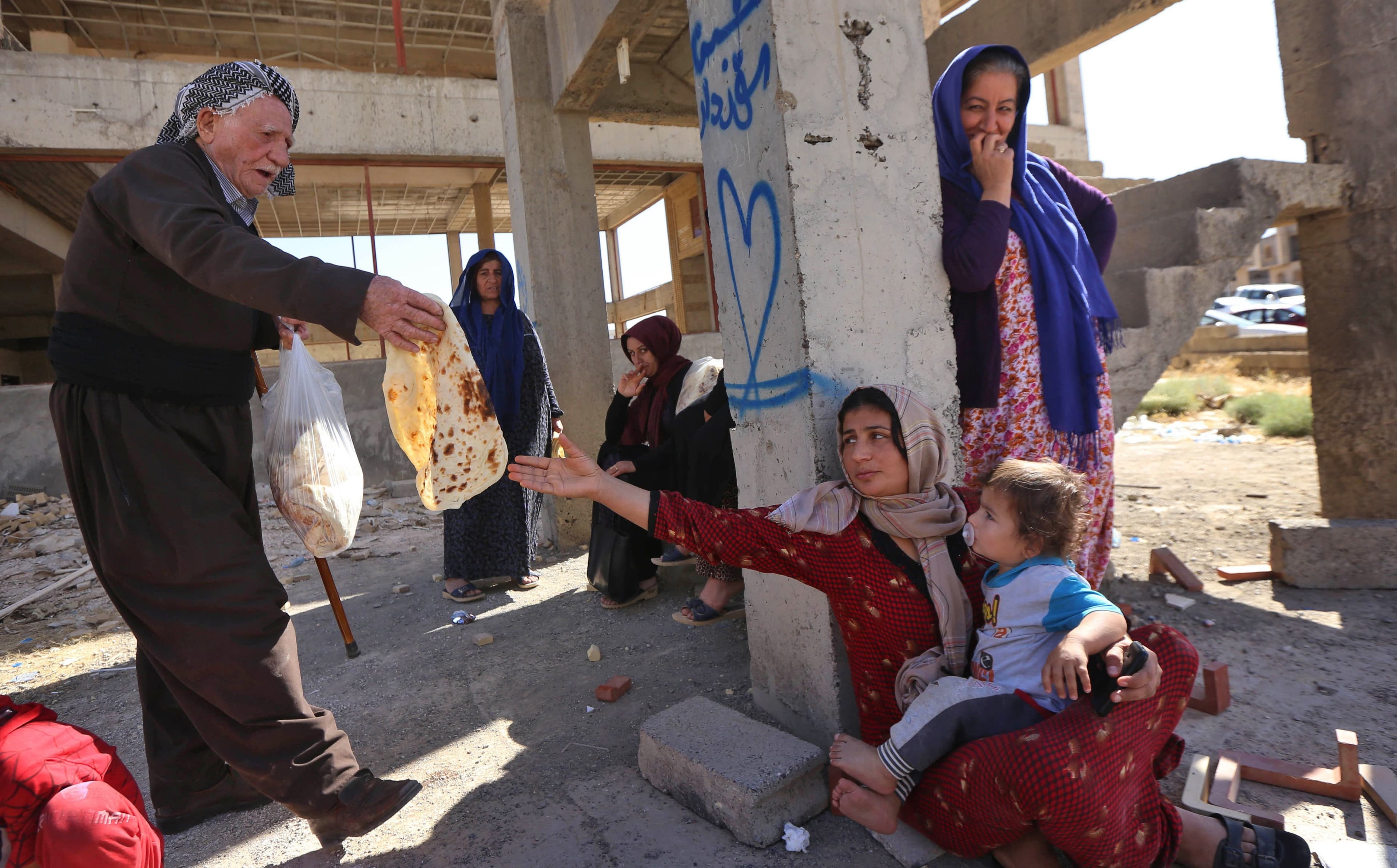 An Erbil man distributes bread to a family displaced from Kirkuk now sheltering at an unfinished housing project in the Kurdistan Region capital on Thursday. Photo: Safin Hamed/AFP