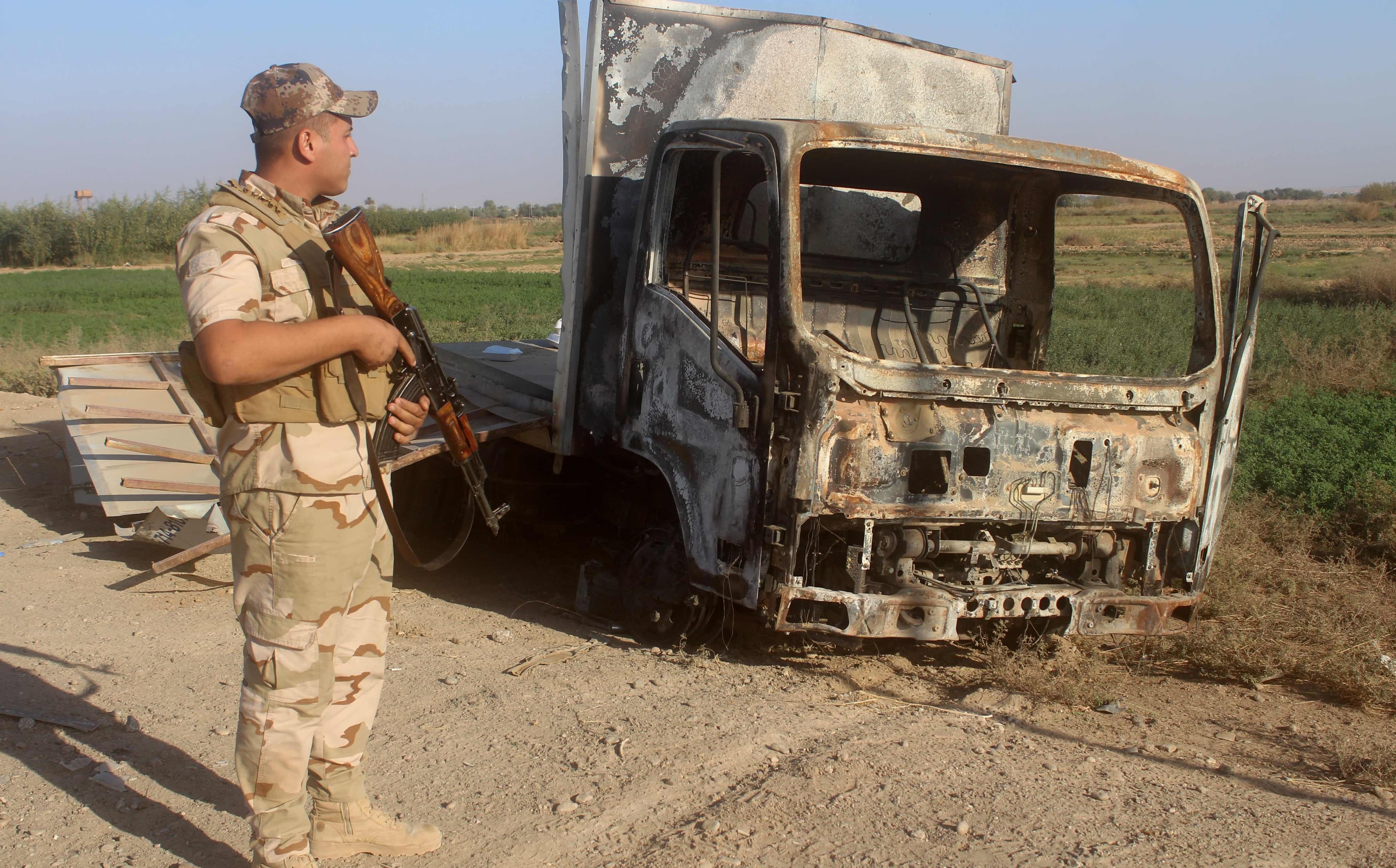 A member of the Iraqi security forces looks at the wreckage of a vehicle in the Rawa area on November 11. Photo: AFP