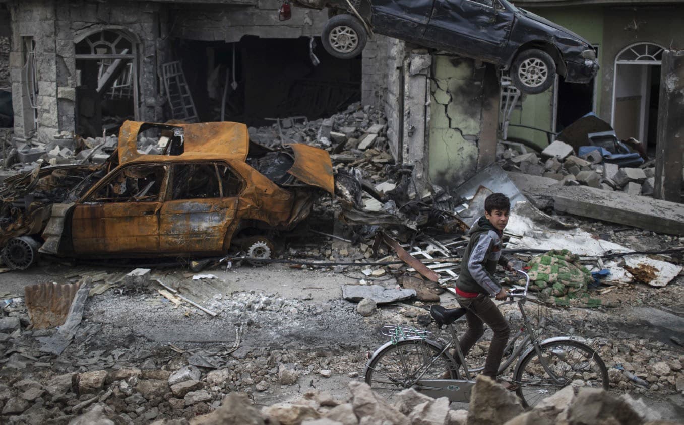 A boy rides his bicycle through the ruins of a Mosul neighbourhood after its liberation from ISIS earlier this year. Photo: Felipe Dana/AP