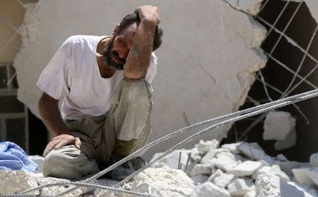 A man waits as Syrian civil defence workers look for survivors under the rubble of a collapsed building following reported air strikes on July 17, 2016 in Aleppo. Photo: AFP/Thaer Mohammed