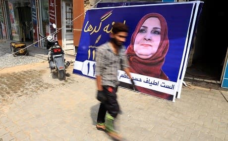 A man walks past a campaign poster for the Hikma movement in Karbala. Photo: Mohammed Sawaf/AFP