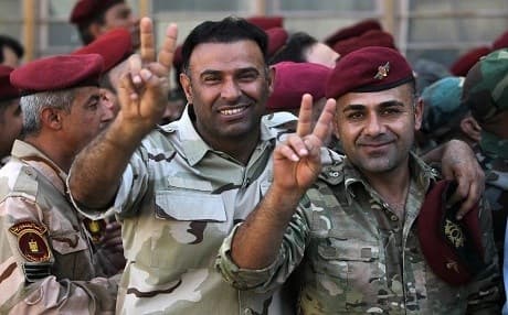Members of the Iraqi security forces flash the "v" sign for victory as they queue in front of a polling station in the Iraqi capital Baghdad to vote ahead of parliamentary elections on May 10, 2018. Photo: Ahmad al-Rubaye | AFP