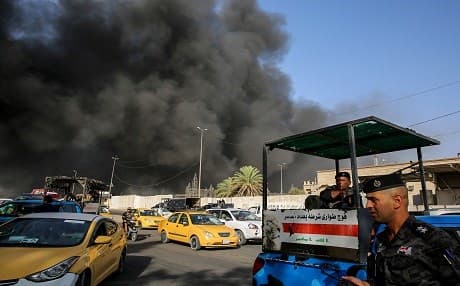 Members of the Iraqi federal police stand outside the country's biggest ballot warehouse, where votes for the eastern Baghdad district were stored, as a column of black smoke billows from a the building on June 10, 2018. Photo: Sabah Arar | AFP