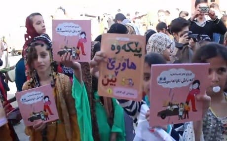 School children in Iran hold aloft Kurdish-language education materials. One reads ‘Let’s be friends.’ Photo: Rudaw