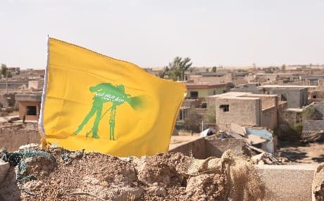 A flag for Hashd al-Shaabi's War Media Cell flies over destroyed parts of southern Shingal in Nineveh province. File photo: Rudaw