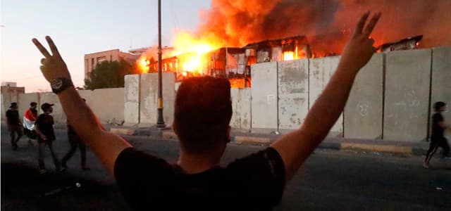 Iraqi protesters watch an official building in flames as they demonstrate against the government and the lack of basic services in Basra on September 6, 2018. Haider Mohammed Ali | AFP