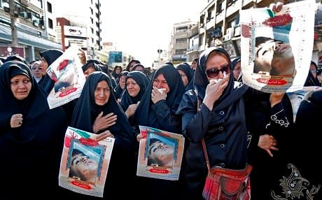 Iranian women hold images of one of the victims, Mohammad Taha Eghdami, 4, during a public funeral ceremony on Monday for those killed during an attack on a military parade in Ahvaz. Photo: Atta Kenare/AFP
