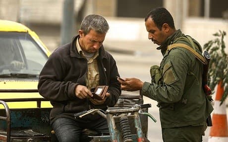 A member of the local security forces inspects the identification of a man in Raqqa in October. ISIS sleeper cells are a daily threat in the city. Photo: Delil Souleiman/AFP