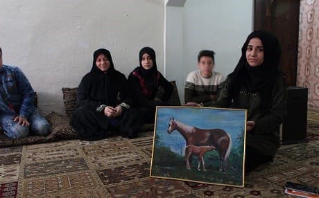 Adiba Sado sits with four of her children in Duhok province on April 1, 2019, left to right: Hor, Rabab, Haider, and Zaynab who holds a painting done by her father Hussein Ilyas Silo. Photo: Hannah Lynch/Rudaw