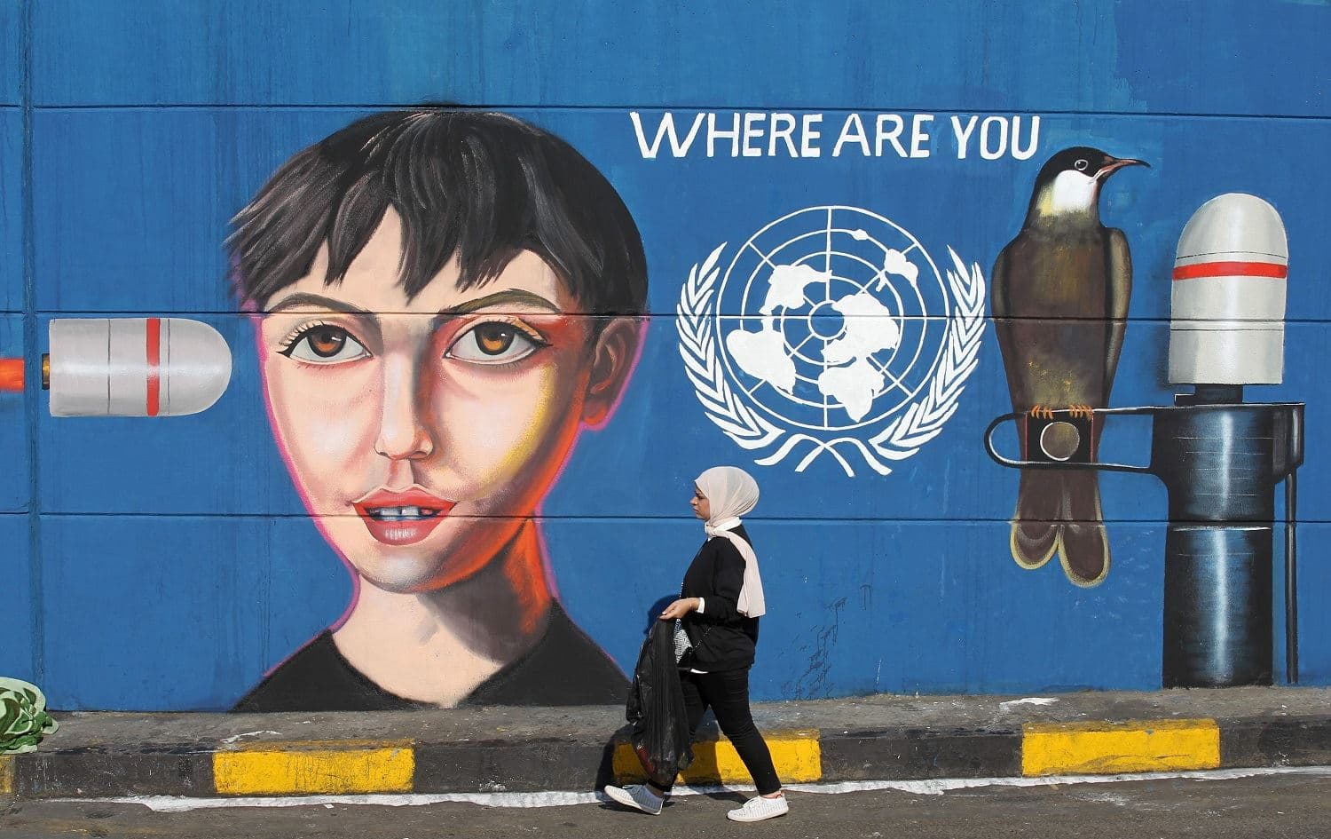 An Iraqi woman walks along a wall covered with a mural painting during an anti-government demonstration in the capital Baghdad's Tahrir square on November 4, 2019. Photo: AFP / Ahmad al-Rubaye