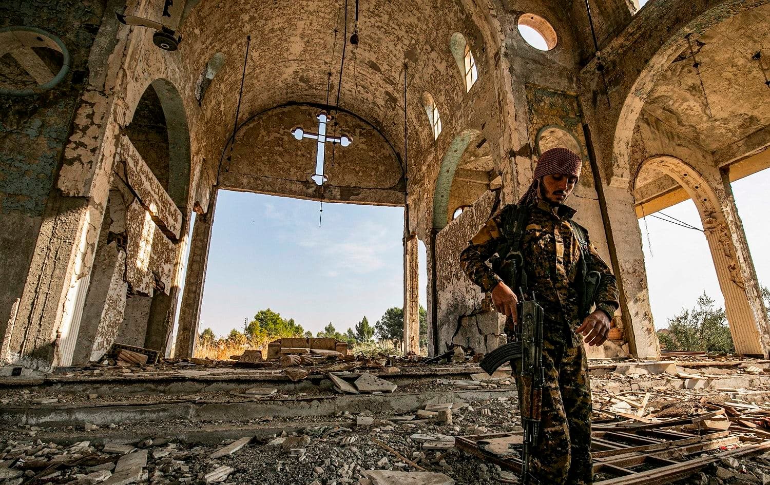A member of the Khabour Guards (MNK) Assyrian Syrian militia walks in the ruins of the Assyrian Church of the Virgin Mary, destroyed by ISIS in 2015, in Tal Nasri, Hasaka, Syria, November 15, 2019. Photo: Delil Souleiman / AFP