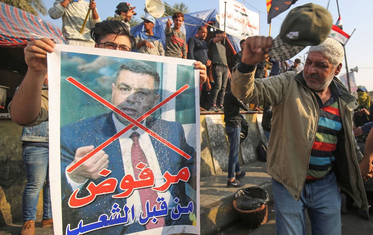 An Iraqi anti-government protester beats with his cap a defaced poster of Assaad al-Aidani, the governor of Basra, during a demonstration in Baghdad's Tahrir Square on December 26, 2019. Photo: AFP / Ahmad Al-Rubaye