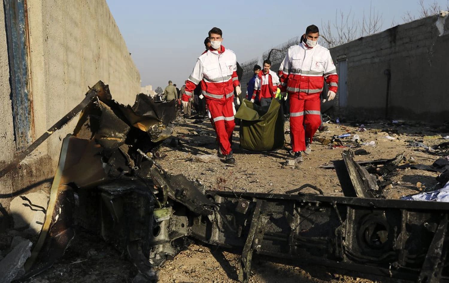 Rescue workers carry the body of a victim of an Ukrainian plane crash among debris of the plane in Shahedshahr, southwest of the capital Tehran, Iran, Wednesday, Jan. 8, 2020. Photo: AP/Ebrahim Noroozi